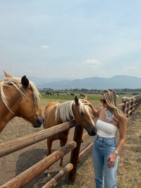 Western revolver print scarf worn outdoors with horse ranch background